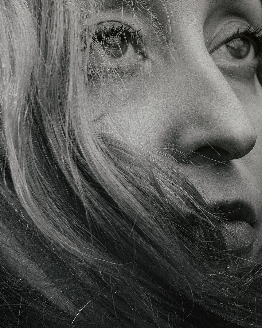 Cinematic black and white close-up of a woman looking up through her hair