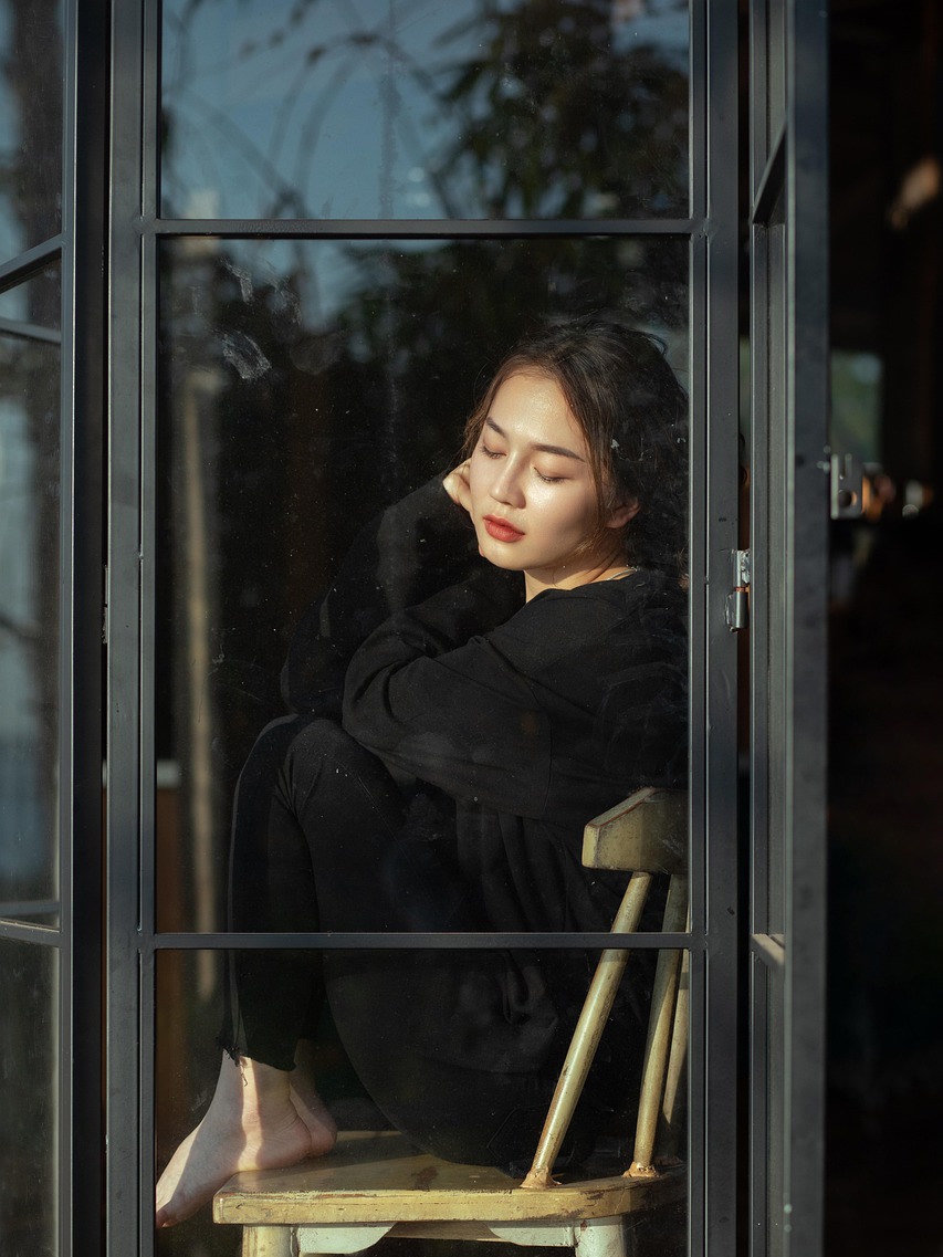 Contemplative portrait of a woman framed by a window grid
